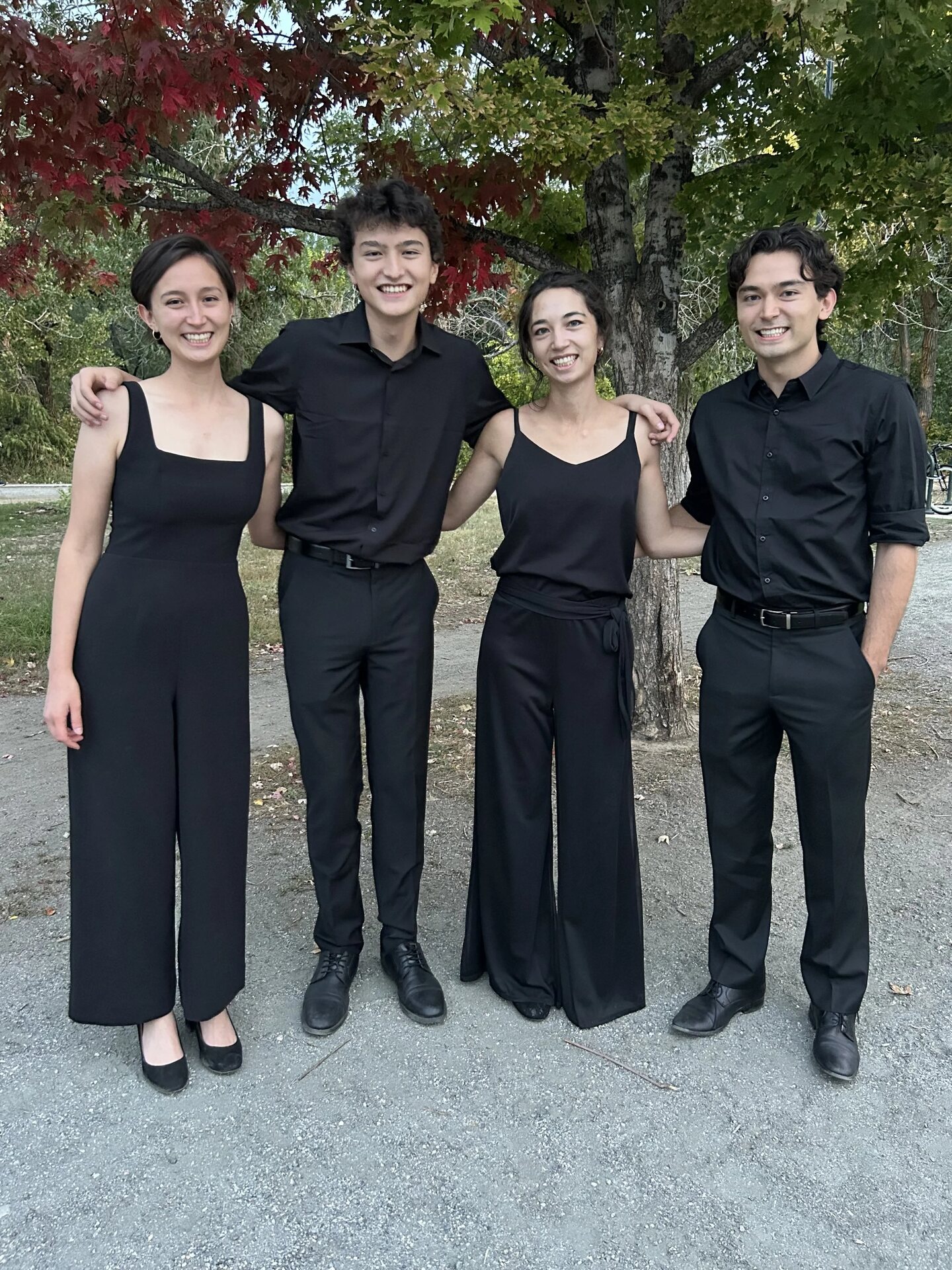 The four members of InTune String Ensemble, dressed in black, standing together outdoors